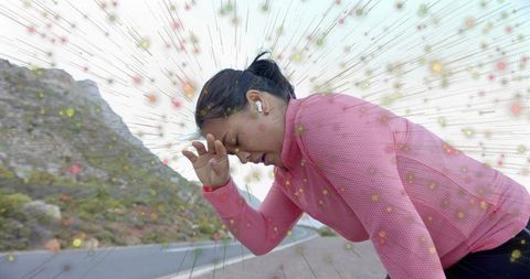 Woman runner in pink attire relieves sweat along mountain road