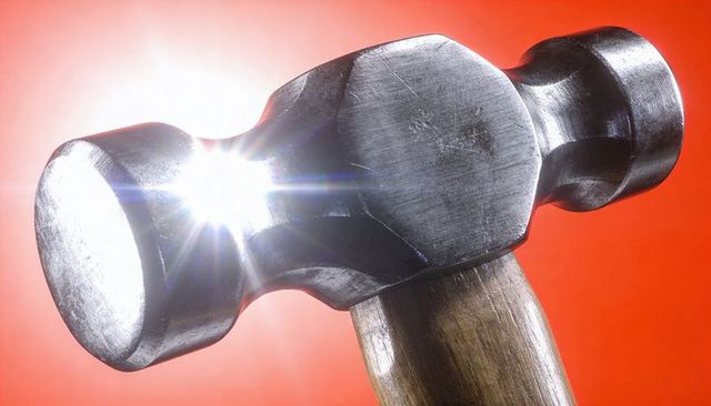 Double-faced hammer close-up showing scratched steel head wooden handle red flare