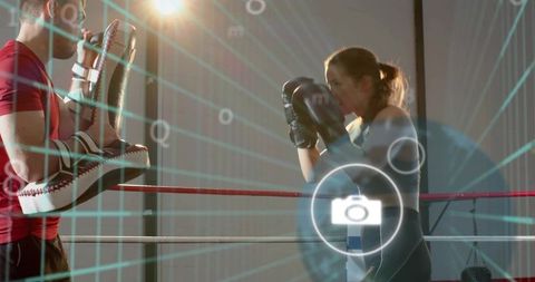 Female boxer throwing punches during high-intensity pad work with coach in boxing ring hudcam