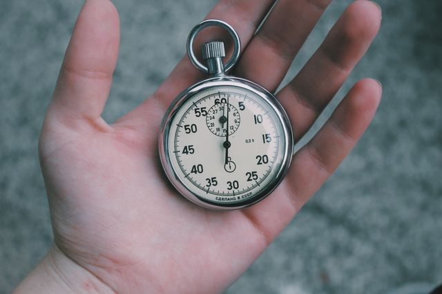 This detailed image of a vintage stopwatch being held in a person's hand focuses on the timeless design and mechanical sophistication of the timekeeping device. Ideal for use in articles or marketing materials related to time management, productivity, sports timing, and vintage collectibles.