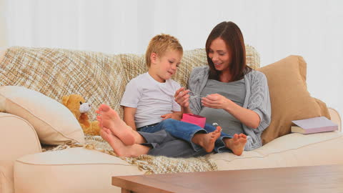 Mother and Son Unwrapping Gift on Cozy Couch