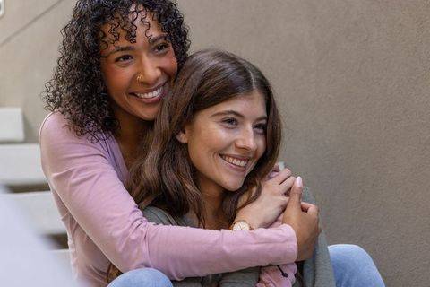 Diverse Women Embracing and Smiling Outdoors Highlighting Friendship