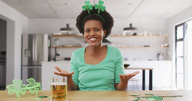 Happy african american woman sitting at table,making image call. st patrick's day, irish tradition, domestic lifestyle, spending free time at home.
