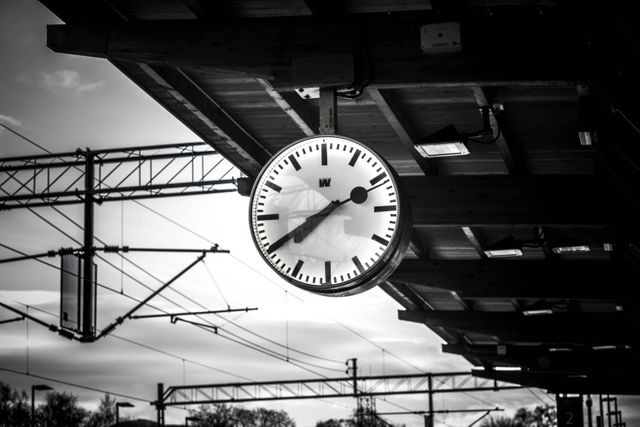 Train station clock in black and white evoking nostalgia and retro aesthetics. Suitable for themes about travel, time, and transportation history. Ideal for use in blog posts, articles about vintage travel, train station history, and as a wall print for a travel-themed decor.