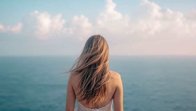 Woman Meditating by Serene Ocean During Tranquil Sunrise