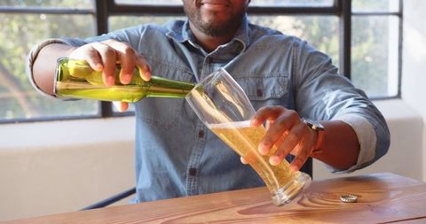 Man Pouring Beer at Home by Sunlit Window for Relaxed Enjoyment
