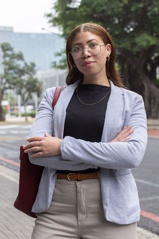 Confident african american businesswoman posing with arms crossed wearing blazer in city
