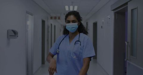 Nurse standing in hospital corridor wearing surgical mask and stethoscope, clinical care