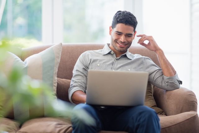 Man sitting on sofa and using laptop in living room - Download Free Stock Photos Pikwizard.com