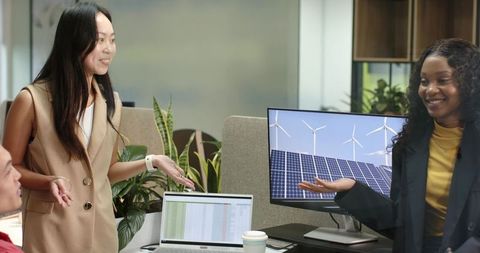 Office team analyzing renewable energy data with laptops and charts