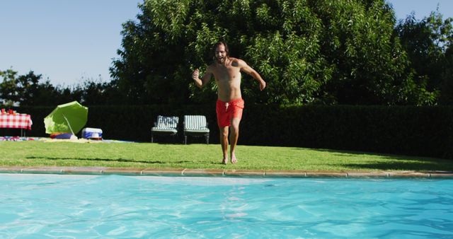 Caucasian man having fun jumping into a swimming pool. hanging out and relaxing outdoors in summer.