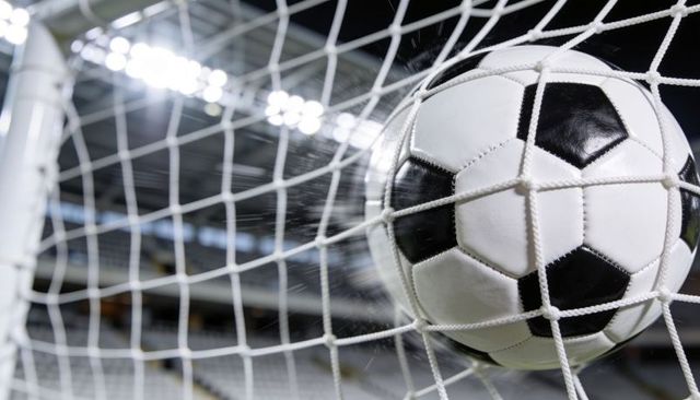Soccer ball hitting net at stadium under floodlights, goal celebration close-up