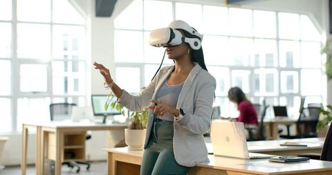 African American woman testing VR headset in modern open-plan office with team observing