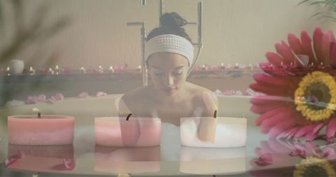 Woman practicing relaxing bath ritual with candles and flowers
