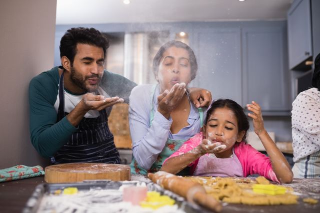 Playful family blowing flour in kitchen at home