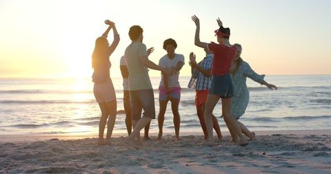 Friends Dancing on Beach at Sunset in a Festive Celebration - Download Free Stock Images Pikwizard.com