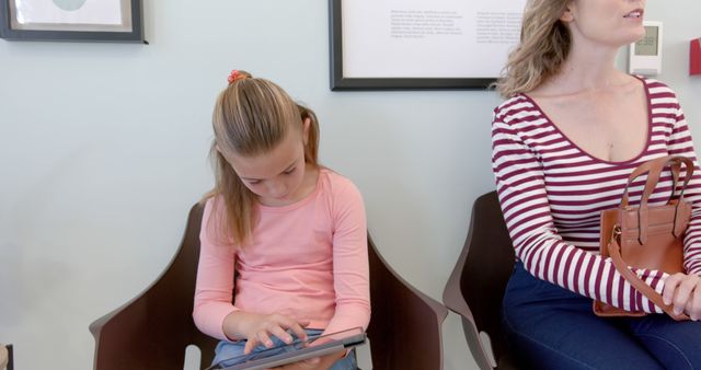 Mother and Daughter Waiting While Child Uses Tablet - Download Free Stock Images Pikwizard.com