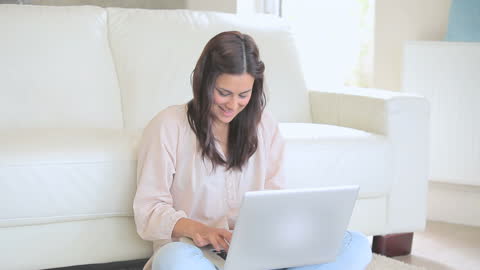 Smiling Woman Sitting on Floor Using Laptop at Home