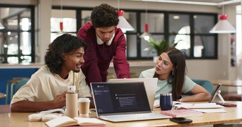 College students collaborating over laptops and notes in modern campus study area