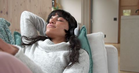 Woman enjoying music in cozy home setting with headphones