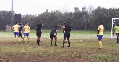 Diverse soccer team strategizing on muddy field for goal
