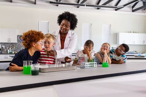African american teacher guiding hands-on chemistry experiment with elementary students