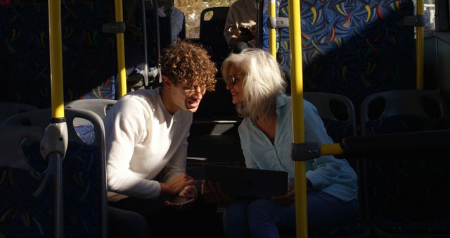 Senior Woman and Young Man Sharing a Laugh and Using Tablet on Public Bus - Download Free Stock Images Pikwizard.com