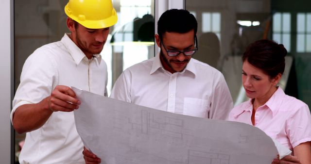 Architect and construction team reviewing blueprints for a building project. Ideal for articles or promotions about architecture, building projects, teamwork in construction, civil engineering, industrial planning, or business collaboration ads.