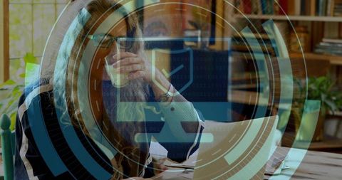 Mature woman working remotely on laptop with coffee and cybersecurity hud overlay