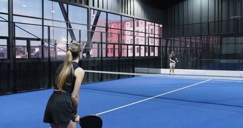 Friends Enjoying Exciting Indoor Padel Match on Blue Turf Court