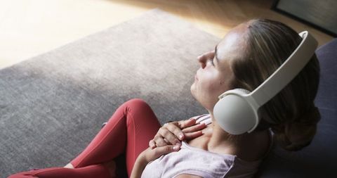 Woman relaxing with headphones on rug listening to music for mindful calm