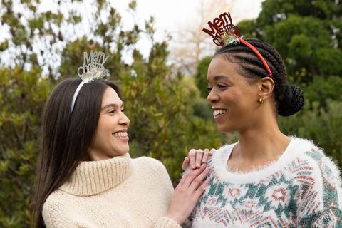 Diverse friends smiling and celebrating christmas outdoors wearing festive headbands