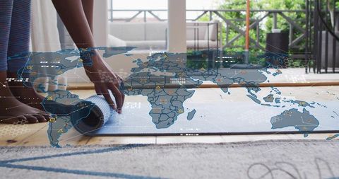 Rolling yoga mat on balcony with global digital map overlay for virtual fitness class