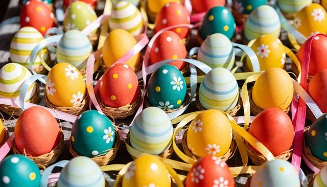 Colorful Hand-Painted Easter Eggs Sitting in Wicker Nests with Pastel Ribbons and Straw