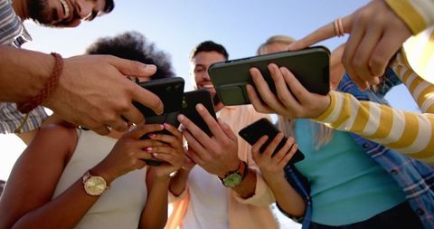 Diverse Group of Friends Enjoying Time with Smartphones Outside