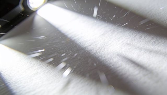 Casting spotlight beam scattering dust motes on textured surface with diagonal bokeh