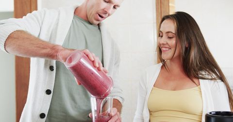Happy Couple Enjoying Smoothie Making in Bright Kitchen