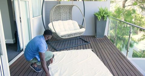 Man Prepares Balcony Space for Relaxation with Blanket