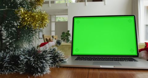 Laptop with Green Screen Near Festive Christmas Tree