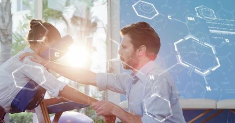 Male Therapist Giving Seated Massage to Woman with Molecular Hex Graphics and Sunlight