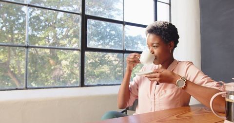 African american woman enjoying coffee break near office window