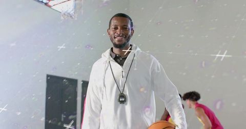 Smiling coach holding basketball on indoor court