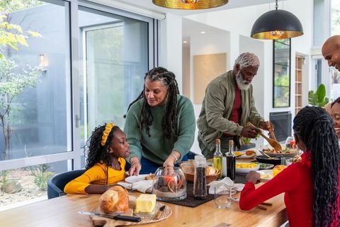 Multigenerational african american family sharing warm meal in bright modern kitchen, togetherness