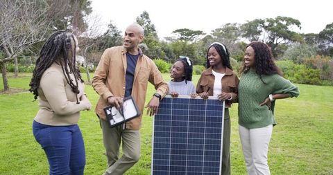 Multigenerational family exploring home solar energy while holding large photovoltaic panel