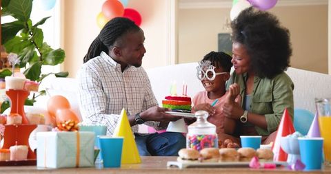 Family celebrating son's birthday at home with cake and balloons