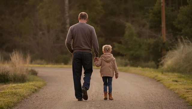 Father and Daughter Walking Hand in Hand on Quiet Country Trail in Warm Evening Light
