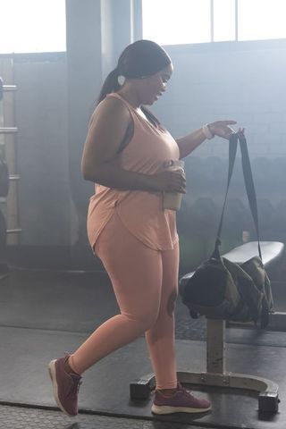 African american woman grabbing camo duffel at gym after workout in pink activewear