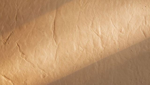 Sunlit crumpled kraft paper texture with diagonal shadow and subtle creases
