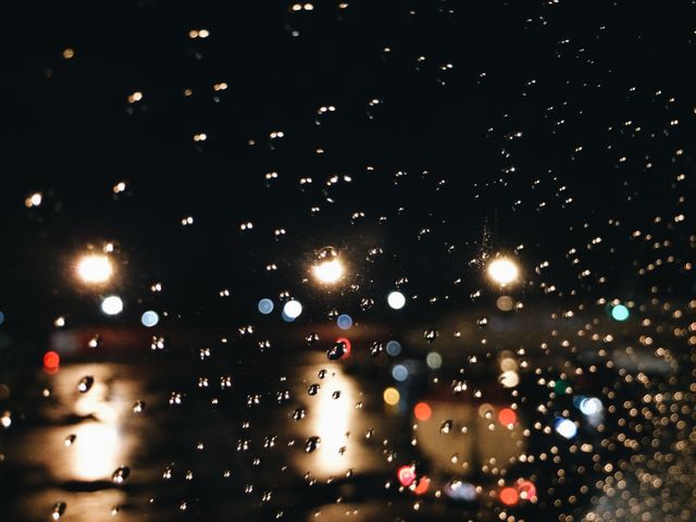 Raindrops on a window with blurred city lights in the background, creating a dreamy and abstract scene. Useful for backgrounds, weather-related content, urban lifestyle themes, and mood-setting visuals in blog posts or social media.
