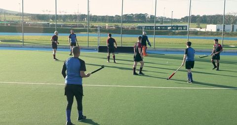 Male Athletes Competing in Field Hockey Match on Turf